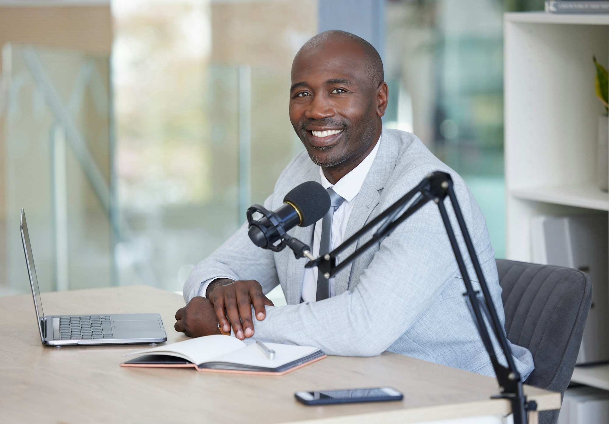 Podcast, portrait and black man with microphone, radio broadcast or content creation in office, lap