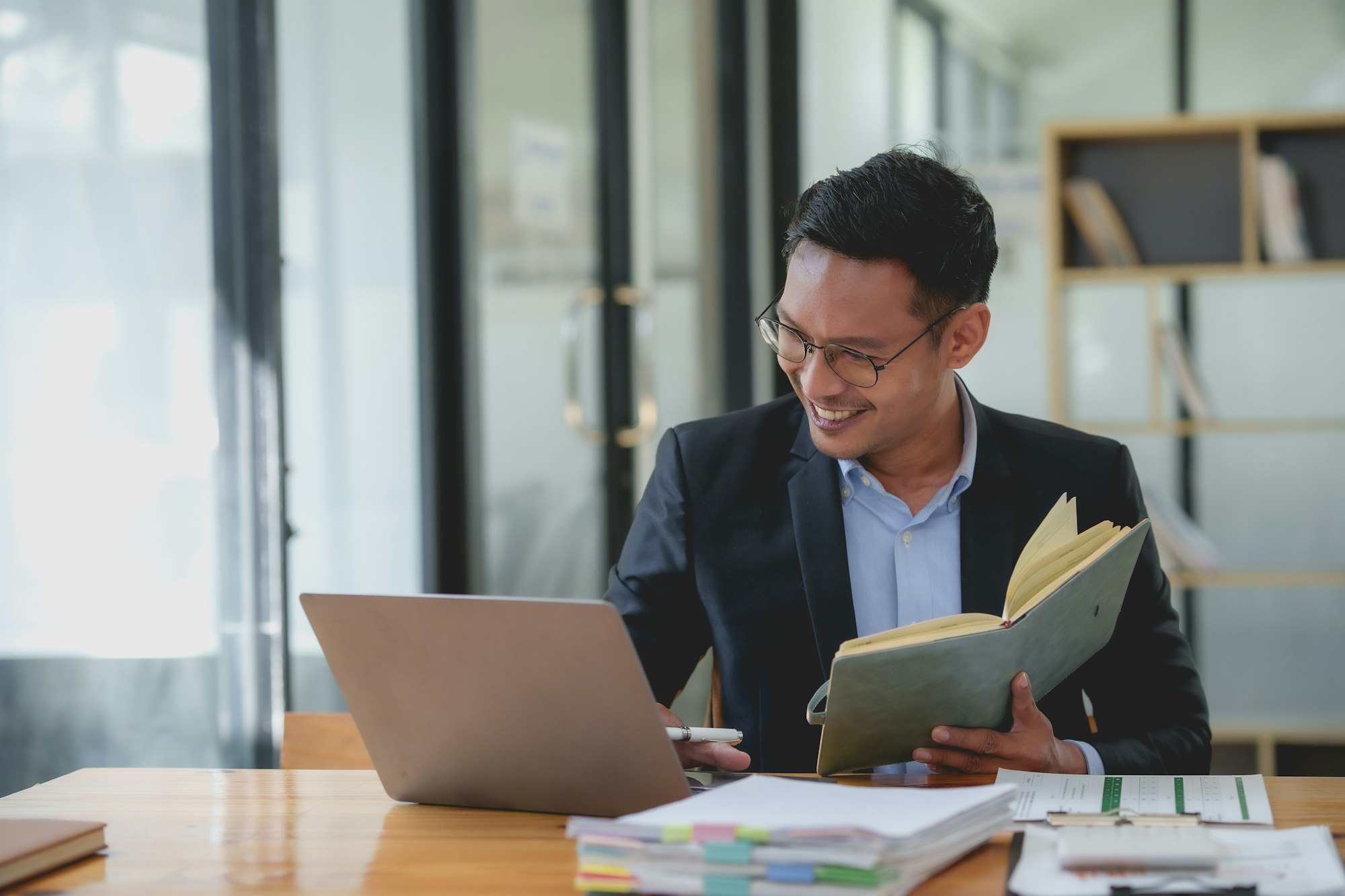 Smiling asian businessman with a notebook giving an online presentation.