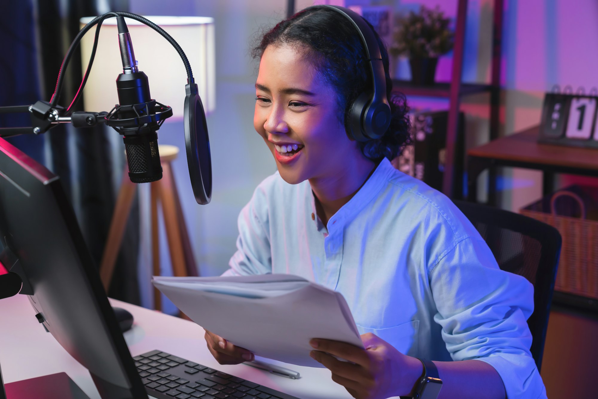 woman wearing headphones and using laptop record podcast at night. Content creator concept.