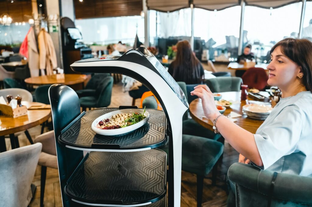 Robot waiter serve food at modern restaurant table.Offering innovation futuristic high-tech